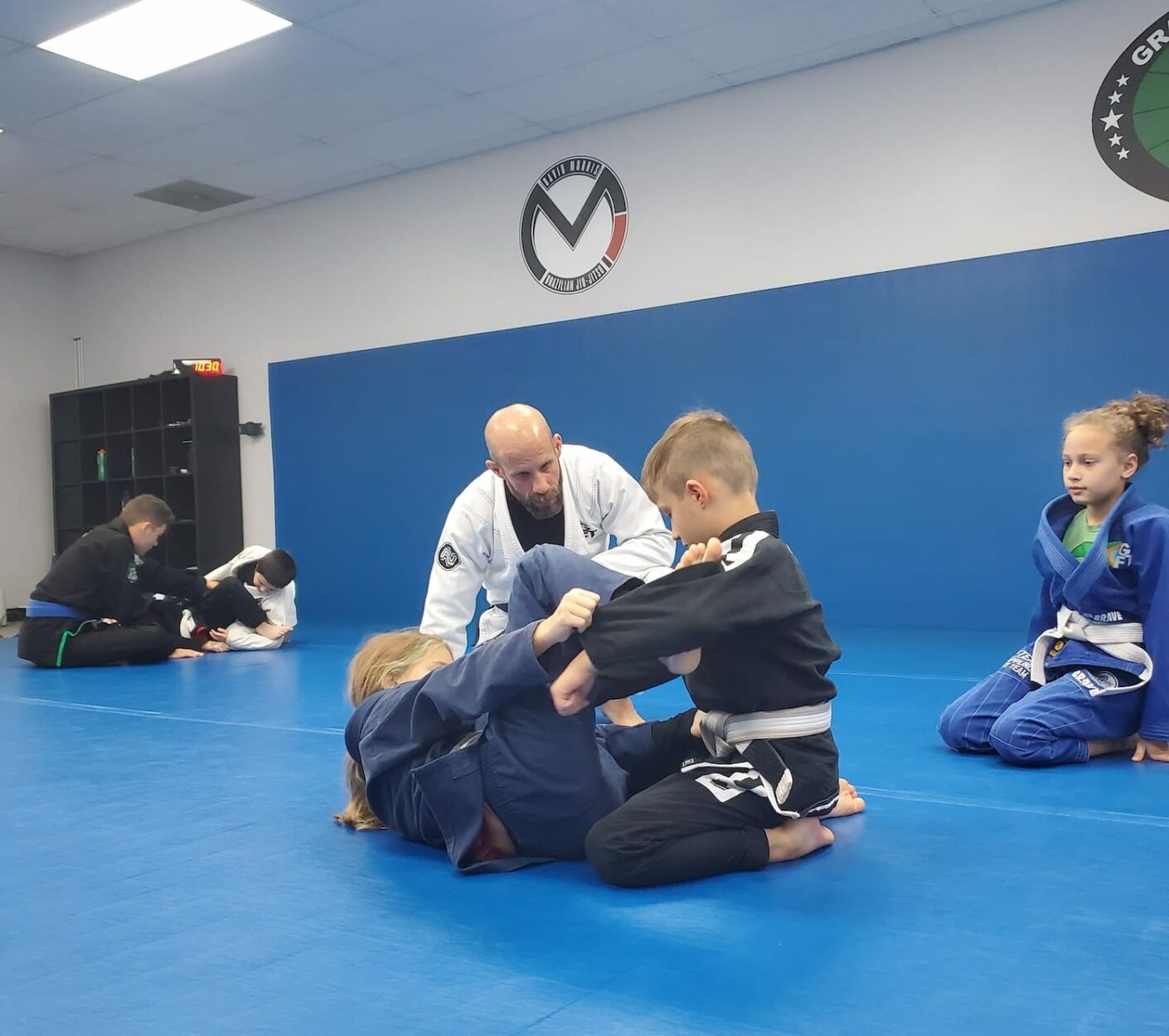 Professor instructing young students how to grapple in a kid's jiu-jitsu class